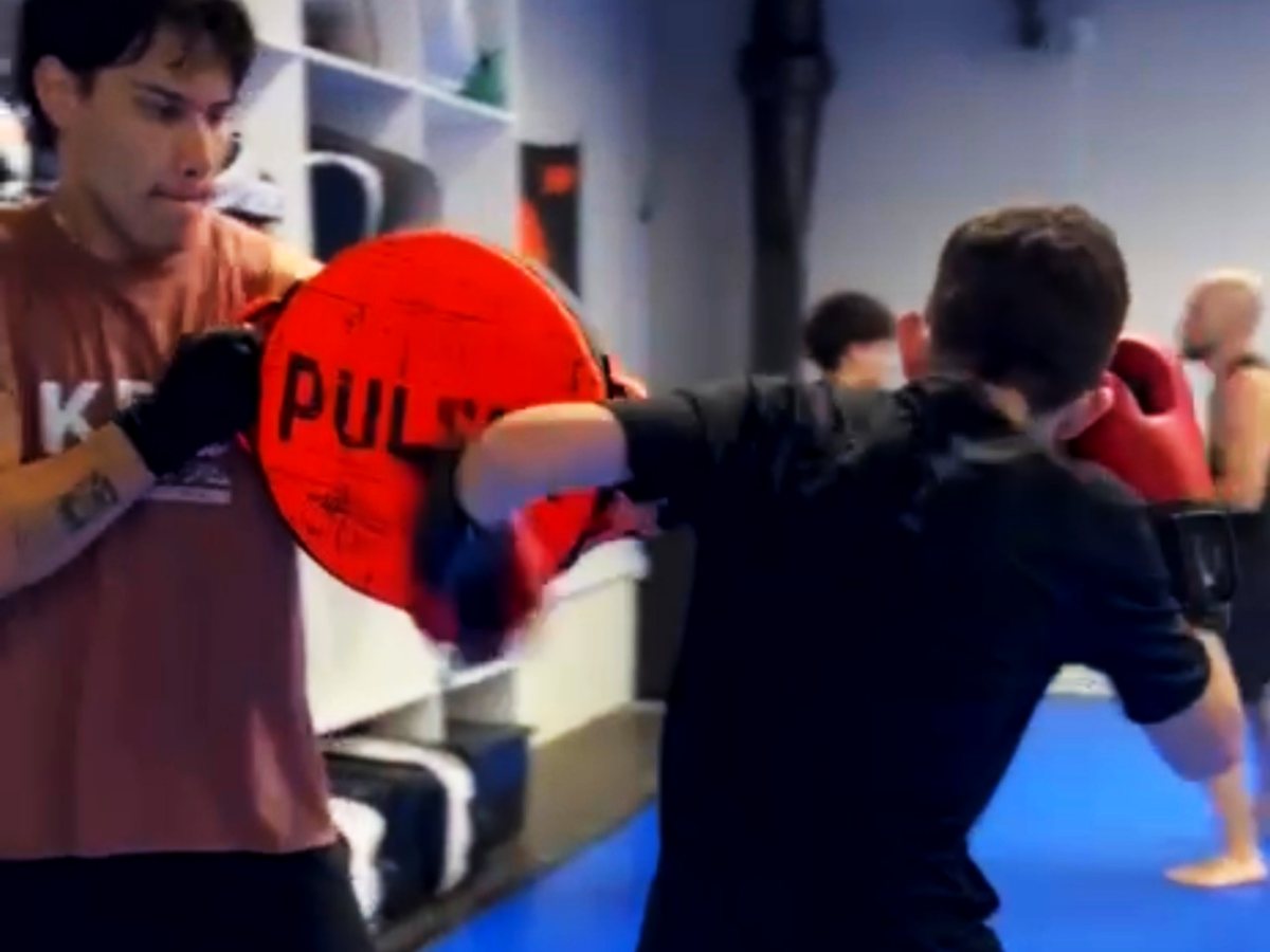 Alunos treinando golpes na manopla durante a aula de boxe